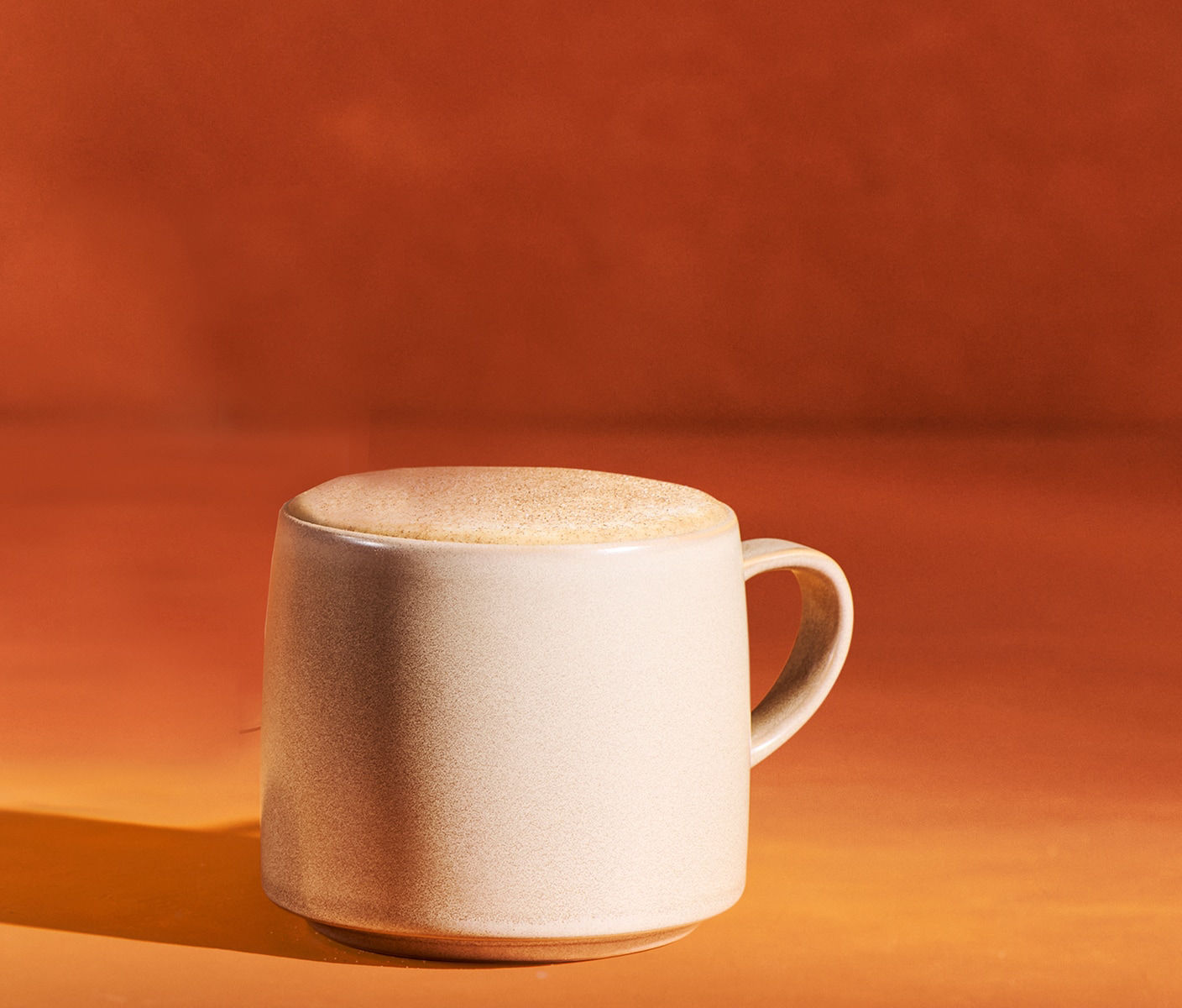 Latte crémeux dans une tasse surmonté de mousse et d’une garniture à la cannelle.