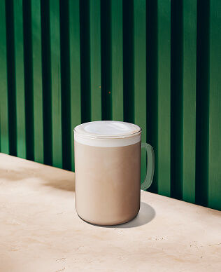 A hot chai latte in a glass mug.